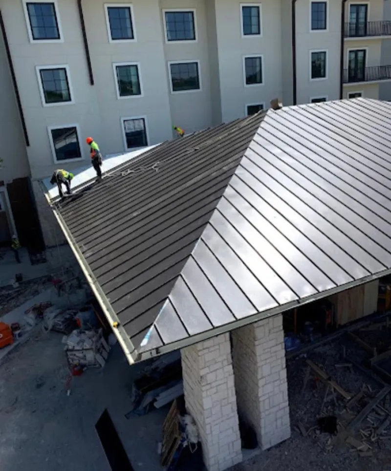 Crew installing standing seam metal roof panels on a commercial project in Prescott